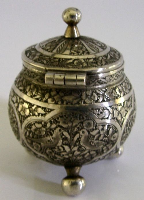 An antique hand-engraved solid silver mustard pot featuring arabesque foliage patterns, a hinged lid with finial, a spoon aperture, and three ball feet. View IV