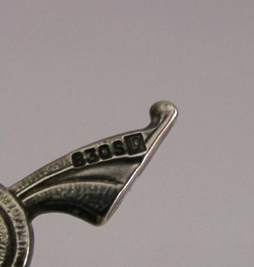 A detailed solid silver model of a Viking longship featuring a dragon head prow, raised sail, pennant flag, and miniature shields along the gunwale. View XII