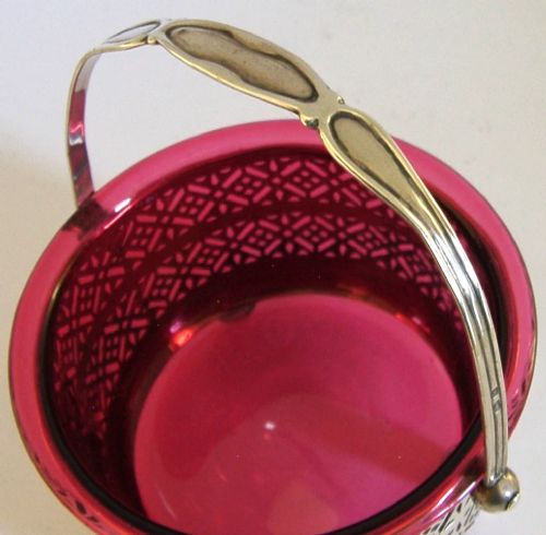 An Edwardian sterling silver pierced basket featuring a lattice geometric pattern, a swing handle, and a fitted cranberry red glass liner. View II
