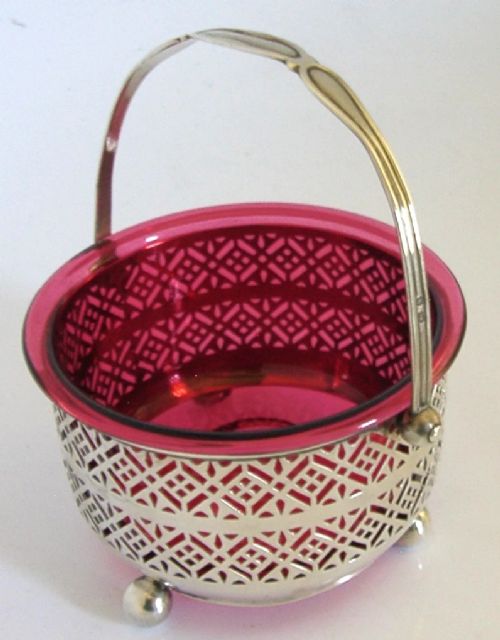 An Edwardian sterling silver pierced basket featuring a lattice geometric pattern, a swing handle, and a fitted cranberry red glass liner. View III