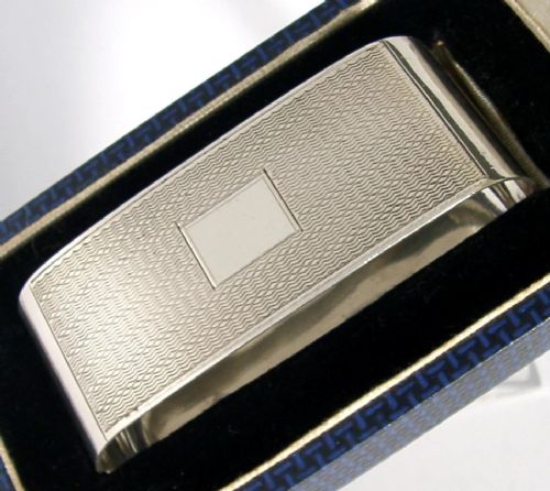 An Art Deco sterling silver napkin ring featuring engine-turned geometric engraving, displayed inside an open blue silk and velvet-lined fitted case. View II