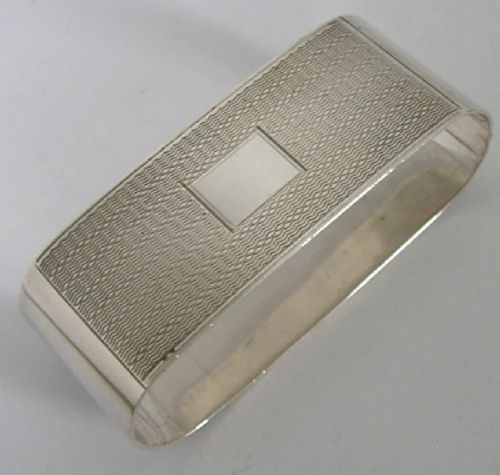 An Art Deco sterling silver napkin ring featuring engine-turned geometric engraving, displayed inside an open blue silk and velvet-lined fitted case. View VI