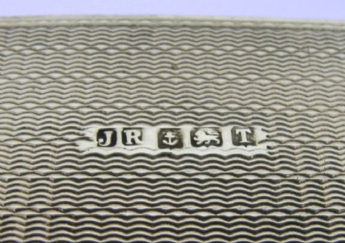 An Art Deco sterling silver napkin ring featuring engine-turned geometric engraving, displayed inside an open blue silk and velvet-lined fitted case. View IX