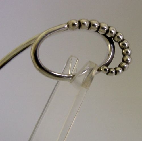 A sterling silver Georg Jensen spoon featuring a curved loop handle detailed with beaded ornamentation and a shallow oval bowl. View IV