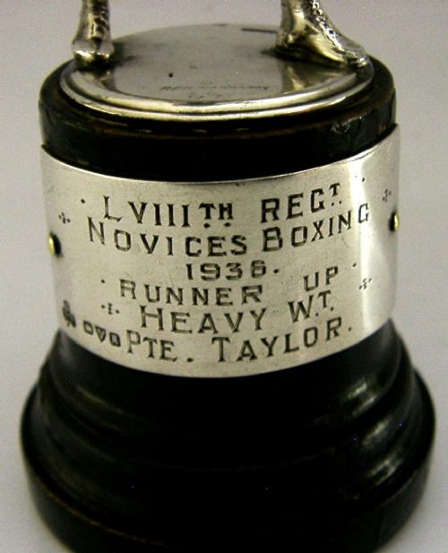 A silver-plated figurine of a boxer in a fighting stance mounted on a dark cylindrical wooden base with an engraved inscription plate. View III