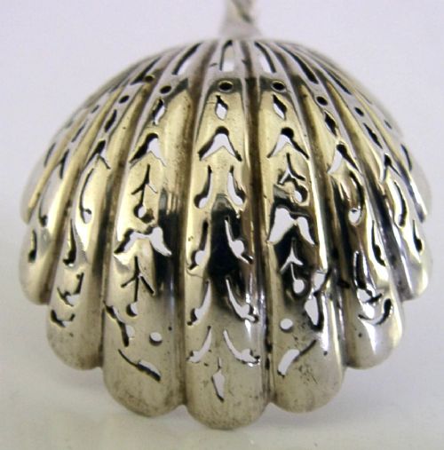 Victorian sterling silver sugar sifter spoon featuring a twisted stem, shell-shaped pierced bowl, and engraved heron crest handle terminal. View V