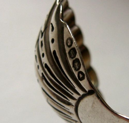 Victorian sterling silver sugar sifter spoon featuring a twisted stem, shell-shaped pierced bowl, and engraved heron crest handle terminal. View VII