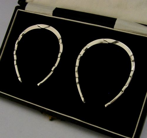 A set of two sterling silver horseshoe-shaped napkin rings presented inside a fitted black presentation case. View III