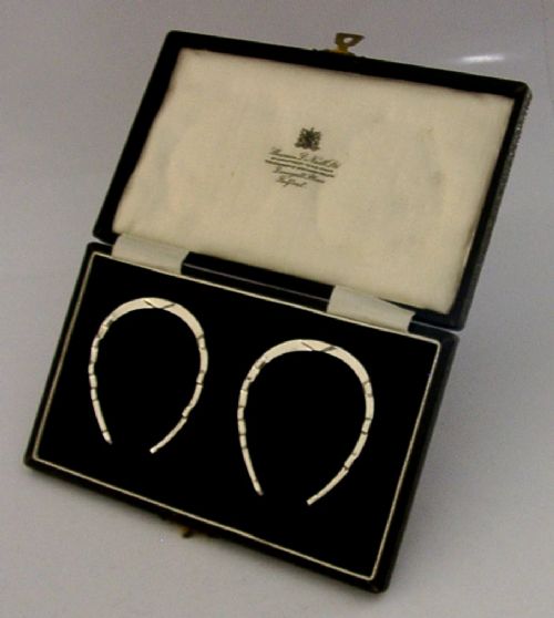 A set of two sterling silver horseshoe-shaped napkin rings presented inside a fitted black presentation case. View IV
