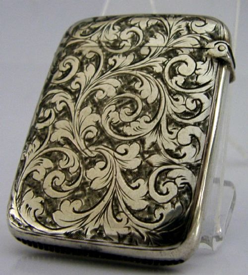Victorian sterling silver vesta case decorated with hand-engraved foliate scrollwork and a central monogrammed shield cartouche. View III