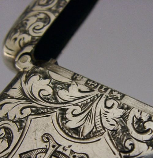Victorian sterling silver vesta case decorated with hand-engraved foliate scrollwork and a central monogrammed shield cartouche. View VIII