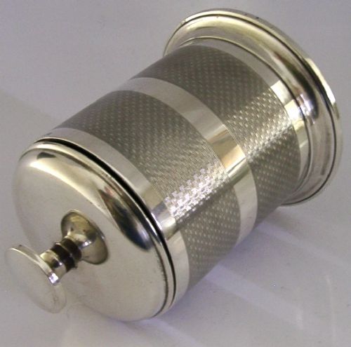 A cylindrical Art Deco sterling silver cigarette dispenser featuring engine-turned patterning, a central polished silver band, and a round knob finial on top. View VI
