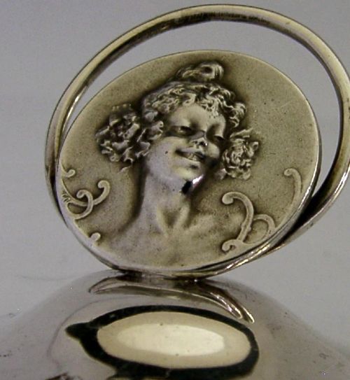 An Edwardian sterling silver menu holder featuring a circular relief of a maidens head set within an oval ring atop a domed base bearing British hallmarks. View III