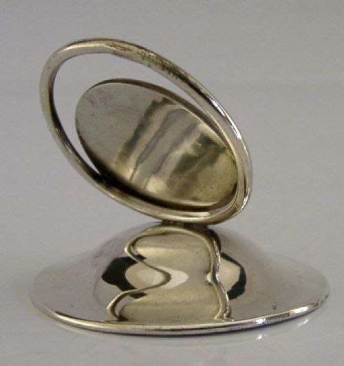 An Edwardian sterling silver menu holder featuring a circular relief of a maidens head set within an oval ring atop a domed base bearing British hallmarks. View V