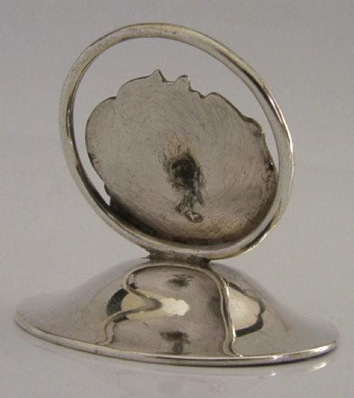 An Art Nouveau sterling silver menu holder featuring a relief face of a maiden with flowing hair set on a domed circular base with British hallmarks. View III