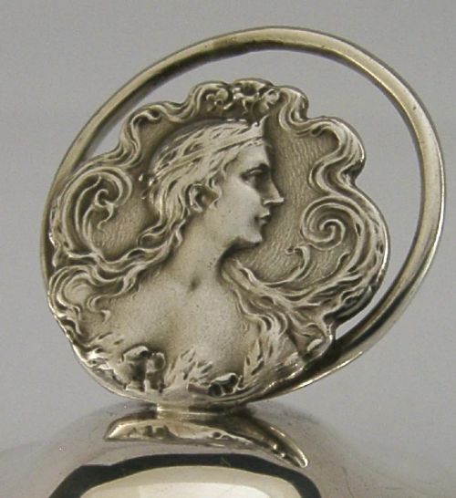An Art Nouveau sterling silver menu holder featuring a relief profile of a maiden with flowing hair framed by a circular wire loop. View III