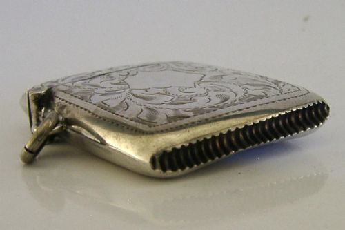 An antique sterling silver vesta case featuring hand-engraved foliate scrollwork, a central shield cartouche, a hinged lid, and a side suspension ring. View VII