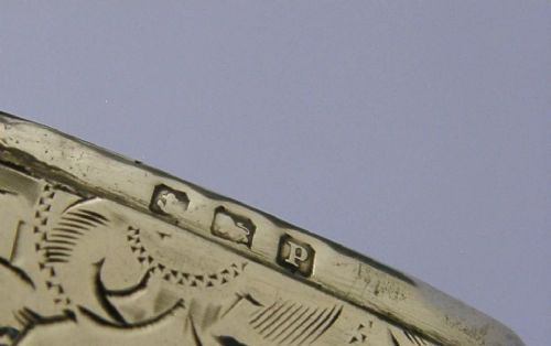 An antique sterling silver vesta case featuring hand-engraved foliate scrollwork, a central shield cartouche, a hinged lid, and a side suspension ring. View IX