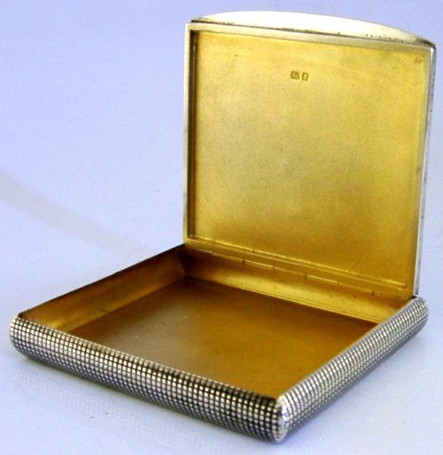 An open sterling silver case displaying an engine-turned grid pattern on the exterior and a gilt metallic interior. View II