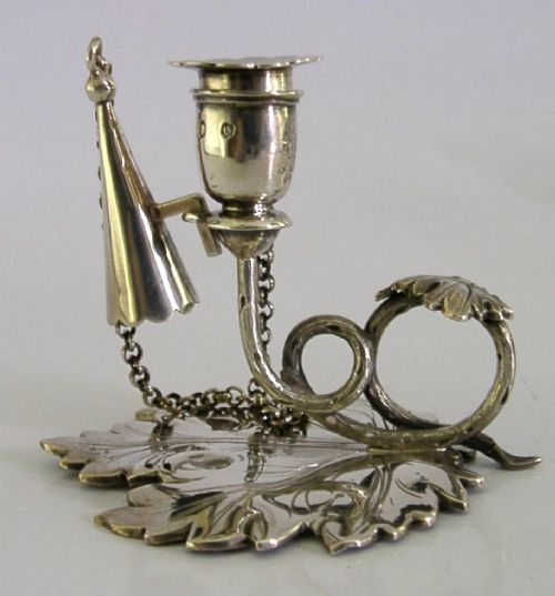 An early Victorian sterling silver chamberstick featuring a shaped leaf base, a coiled vine handle, and an attached chain with a conical snuffer. View II