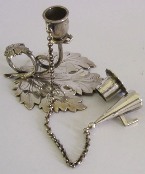 An early Victorian sterling silver chamberstick featuring a shaped leaf base, a coiled vine handle, and an attached chain with a conical snuffer. View IV