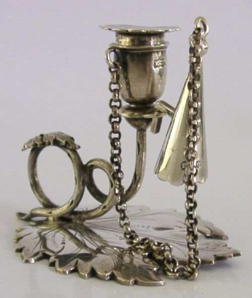 An early Victorian sterling silver chamberstick featuring a shaped leaf base, a coiled vine handle, and an attached chain with a conical snuffer. View V