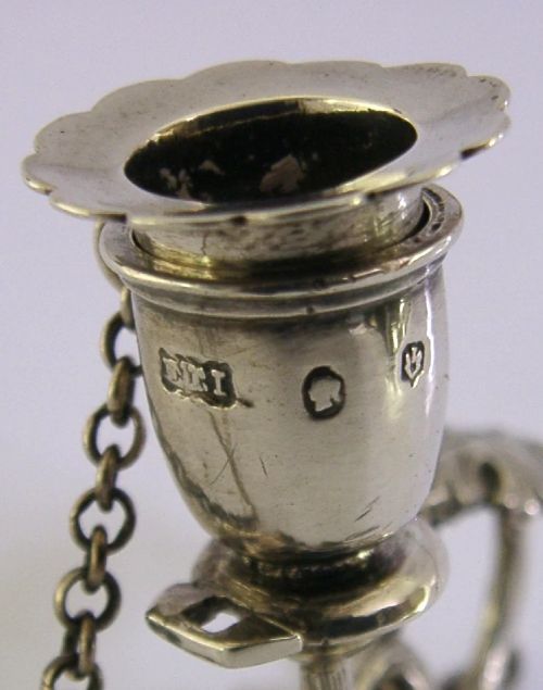 An early Victorian sterling silver chamberstick featuring a shaped leaf base, a coiled vine handle, and an attached chain with a conical snuffer. View IX