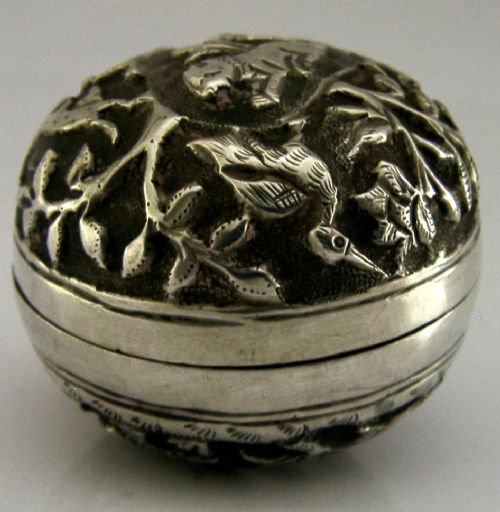 A circular solid silver box with relief repousse carvings depicting an elephant and palm trees in a jungle landscape. View VI