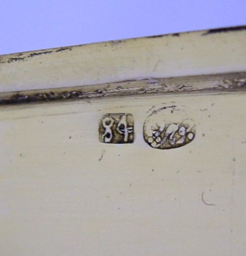 A rectangular solid silver cigarette case featuring dense hand-engraved bird and foliate patterns with a gold monogram in the upper corner. View IX