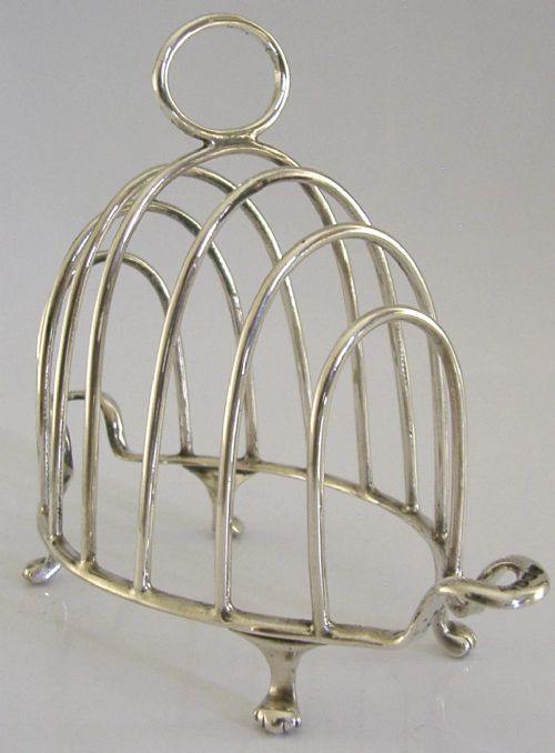 A 1925 English sterling silver six-slice toast rack featuring arched wire dividers, a top ring handle, and small paw feet. View III