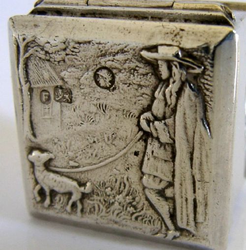 A small rectangular sterling silver box with a hinged lid featuring a raised relief scene of a figure walking a dog near a rustic building. View II