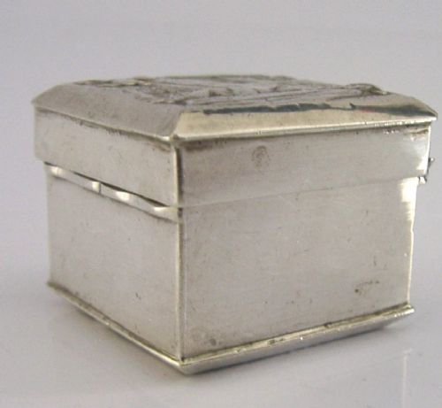 A small rectangular sterling silver box with a hinged lid featuring a raised relief scene of a figure walking a dog near a rustic building. View VII