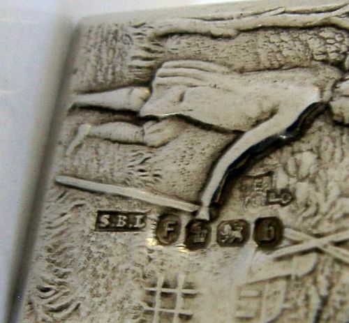A small rectangular sterling silver box with a hinged lid featuring a raised relief scene of a figure walking a dog near a rustic building. View X