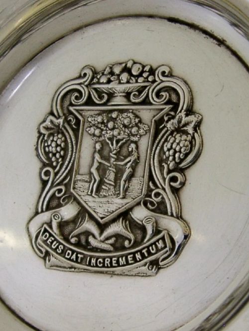 A circular sterling silver dish featuring the embossed coat of arms of the Worshipful Company of Fruiterers in the centre with hallmarks near the rim. View II