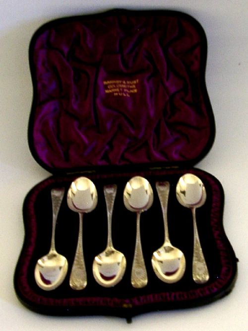 A set of six engraved Victorian sterling silver spoons arranged inside a black fitted presentation case lined with deep purple velvet. View V