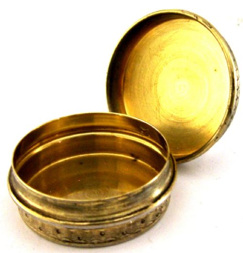 A circular French sterling silver gilt trinket box featuring engine-turned guilloche detailing and a decorative laurel leaf border. View III