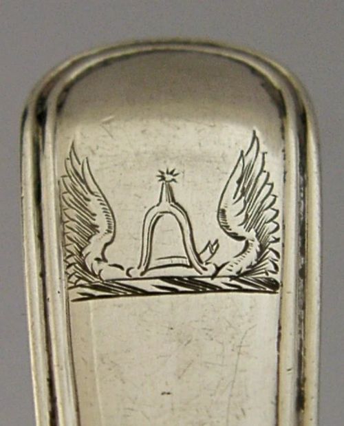 A Victorian sterling silver tea caddy spoon featuring a broad shovel-shaped bowl and an engraved crest on the handle. View III