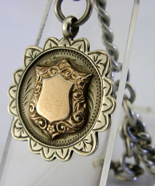 A solid sterling silver double Albert watch chain featuring curb links, a T-bar, two swivel clasps, and a decorative shield fob. View III