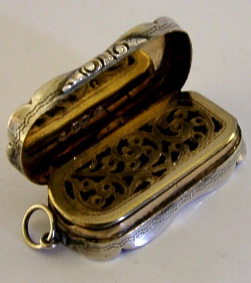 An antique Victorian sterling silver vinaigrette box featuring a shaped lobed outline, engine-turned geometric engraving, and a central engraved monogram cartouche. View III