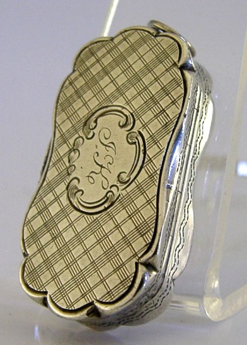An antique Victorian sterling silver vinaigrette box featuring a shaped lobed outline, engine-turned geometric engraving, and a central engraved monogram cartouche. View IX