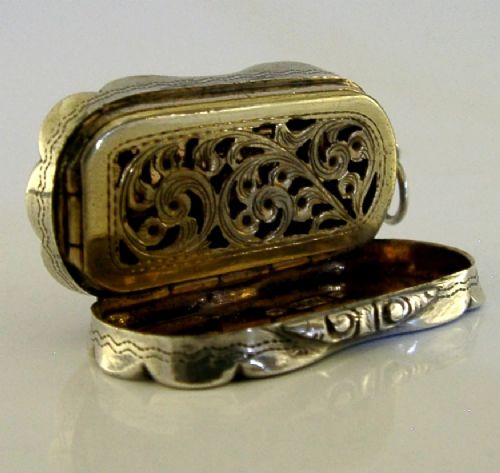 An antique Victorian sterling silver vinaigrette box featuring a shaped lobed outline, engine-turned geometric engraving, and a central engraved monogram cartouche. View X