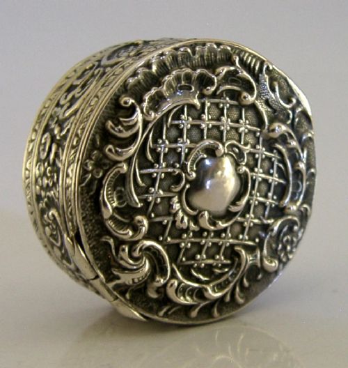 A circular French solid silver pill box with Rococo Revival lattice and floral scroll embossing. View III