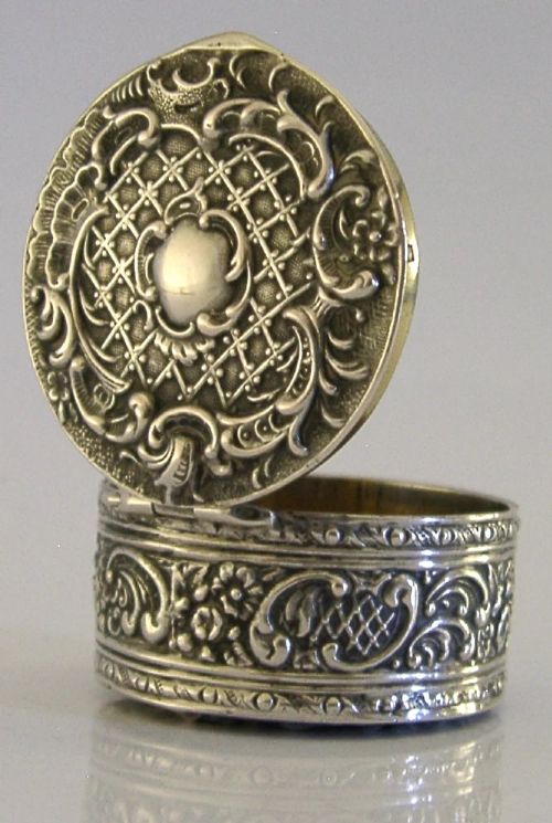 A circular French solid silver pill box with Rococo Revival lattice and floral scroll embossing. View V