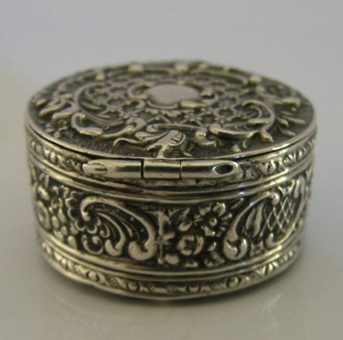 A circular French solid silver pill box with Rococo Revival lattice and floral scroll embossing. View VI
