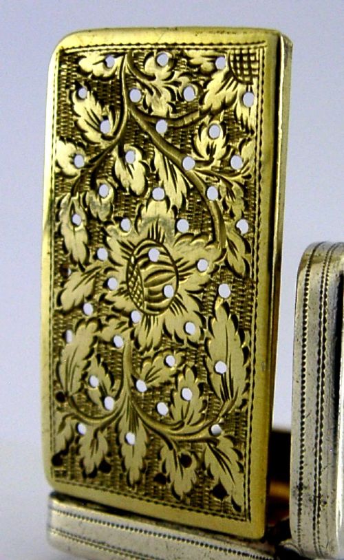 An open rectangular Georgian sterling silver vinaigrette box displaying an engraved exterior and a pierced gold-gilded inner grille featuring floral leaf patterns. View II