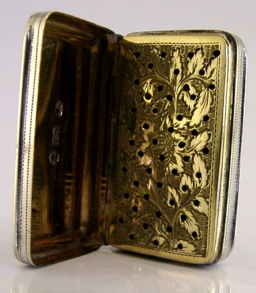 An open rectangular Georgian sterling silver vinaigrette box displaying an engraved exterior and a pierced gold-gilded inner grille featuring floral leaf patterns. View V