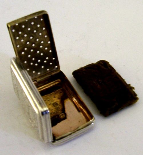 An open rectangular Georgian sterling silver vinaigrette box displaying an engraved exterior and a pierced gold-gilded inner grille featuring floral leaf patterns. View VII