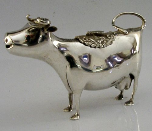 A sterling silver novelty cow creamer featuring a hollow cast body, a hinged lid decorated with floral motifs on the back, and a looped tail handle. View IV