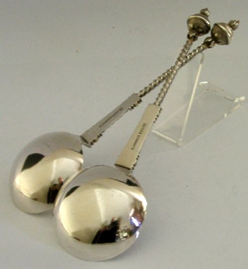 A pair of antique Norwegian silver serving spoons featuring round engraved bowls, twisted wire stems, and decorative knop finials. View V