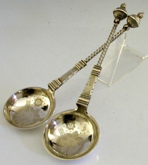 A pair of antique Norwegian silver serving spoons featuring round engraved bowls, twisted wire stems, and decorative knop finials. View VIII